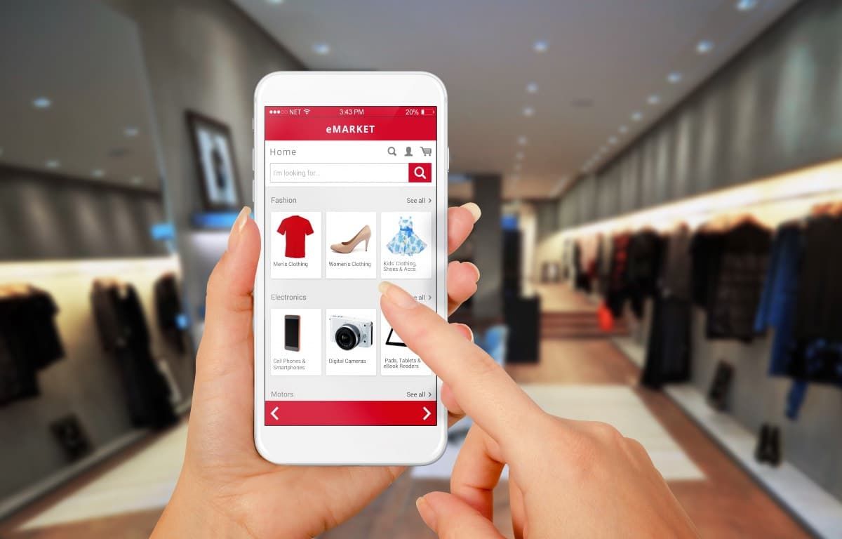 Femme faisant des achats en ligne depuis son smartphone avec un magasin en arriere plan.